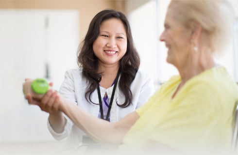 Asian female assisting elderly woman with physical therapy